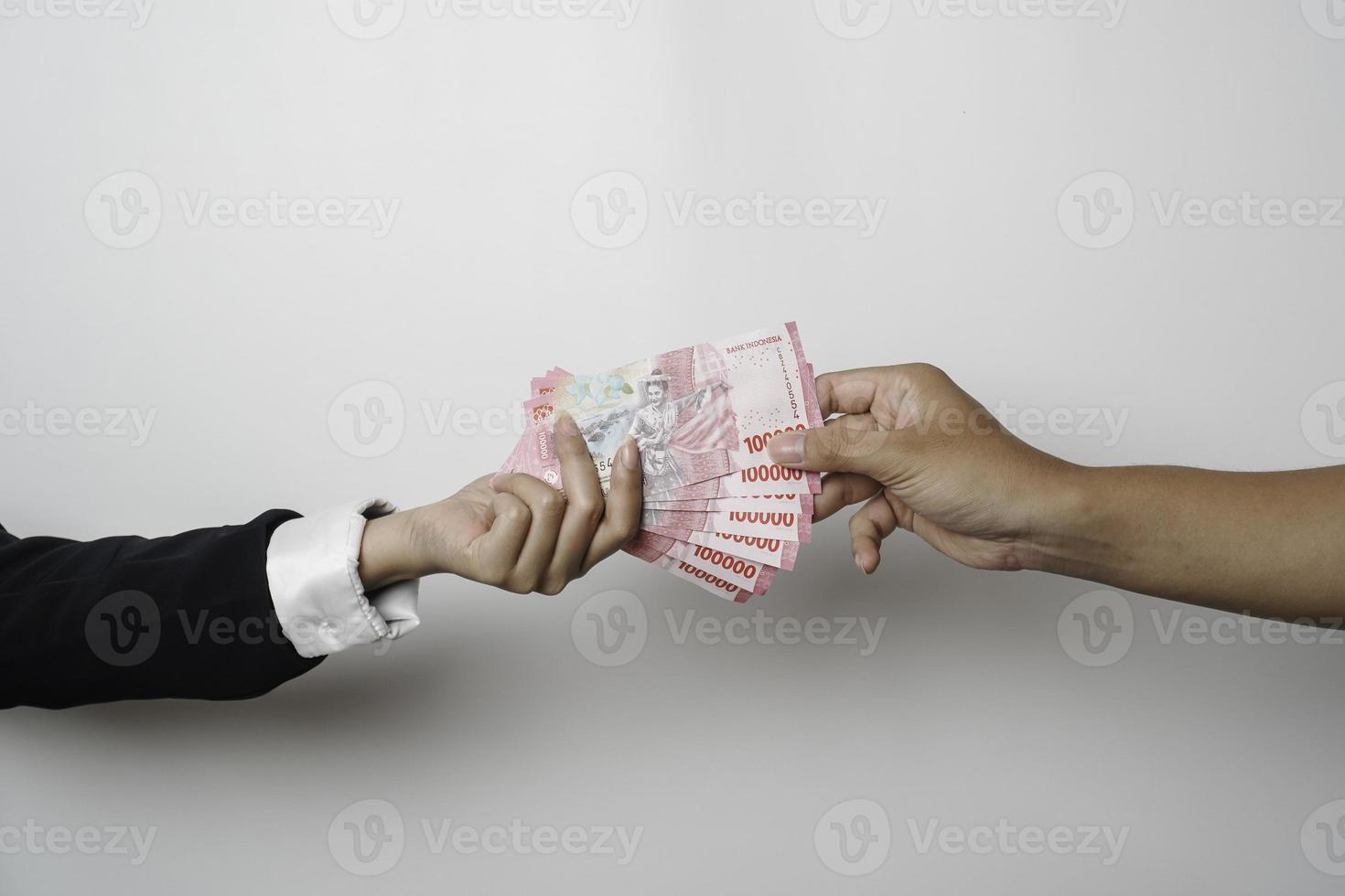 A portrait of businessman giving money in Indonesian Rupiah for business deal or payment or charity photo