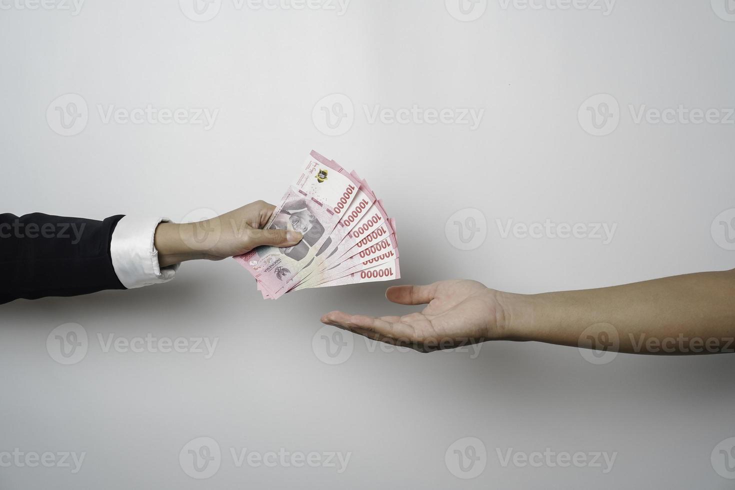 A portrait of businessman giving money in Indonesian Rupiah for business deal or payment or charity photo