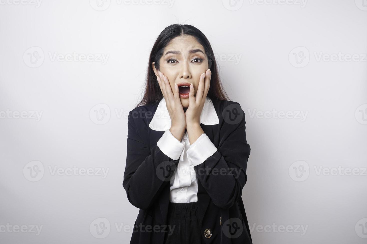 A portrait of an Asian business woman wearing a black suit isolated by white background looks depressed photo