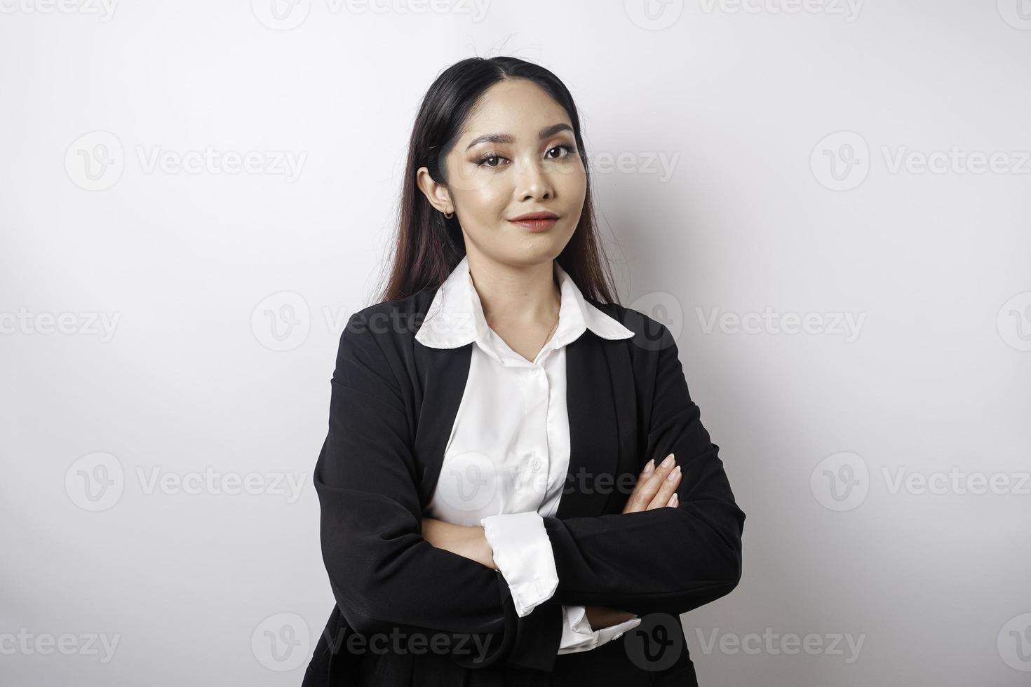 retrato de una jefa asiática sonriente y confiada con traje negro parada con los brazos cruzados y mirando la cámara aislada sobre fondo blanco foto