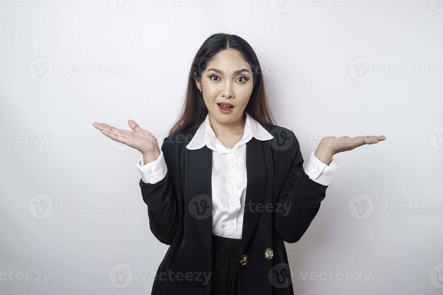 A portrait of an Asian girl boss wearing a black suit looks so confused between choices, isolated by a white background photo