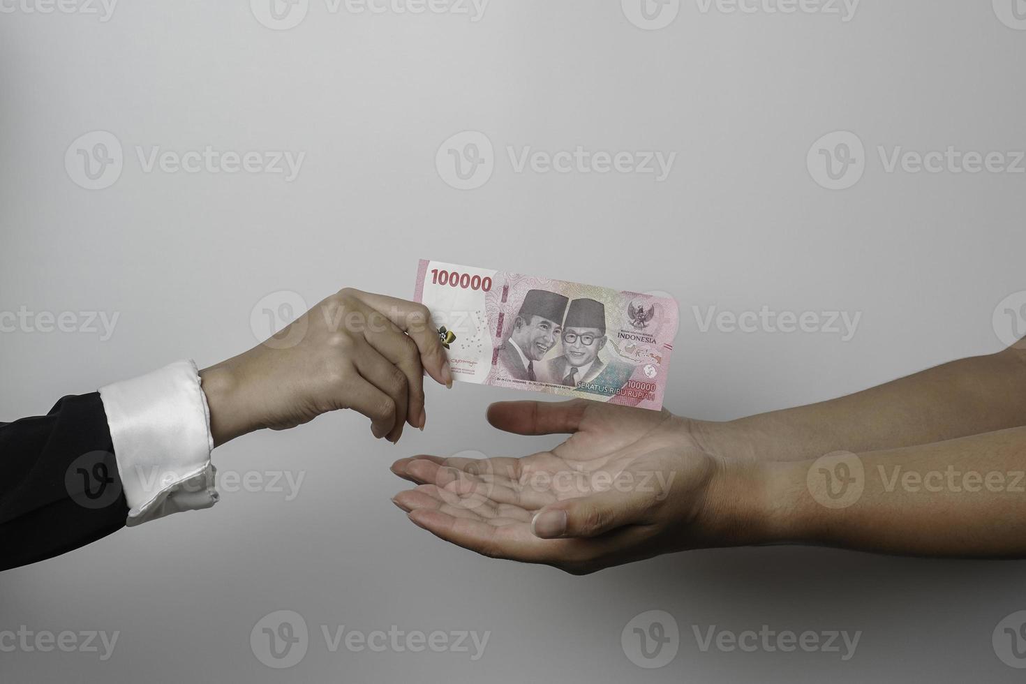 A portrait of businessman giving money in Indonesian Rupiah for business deal or payment or charity photo