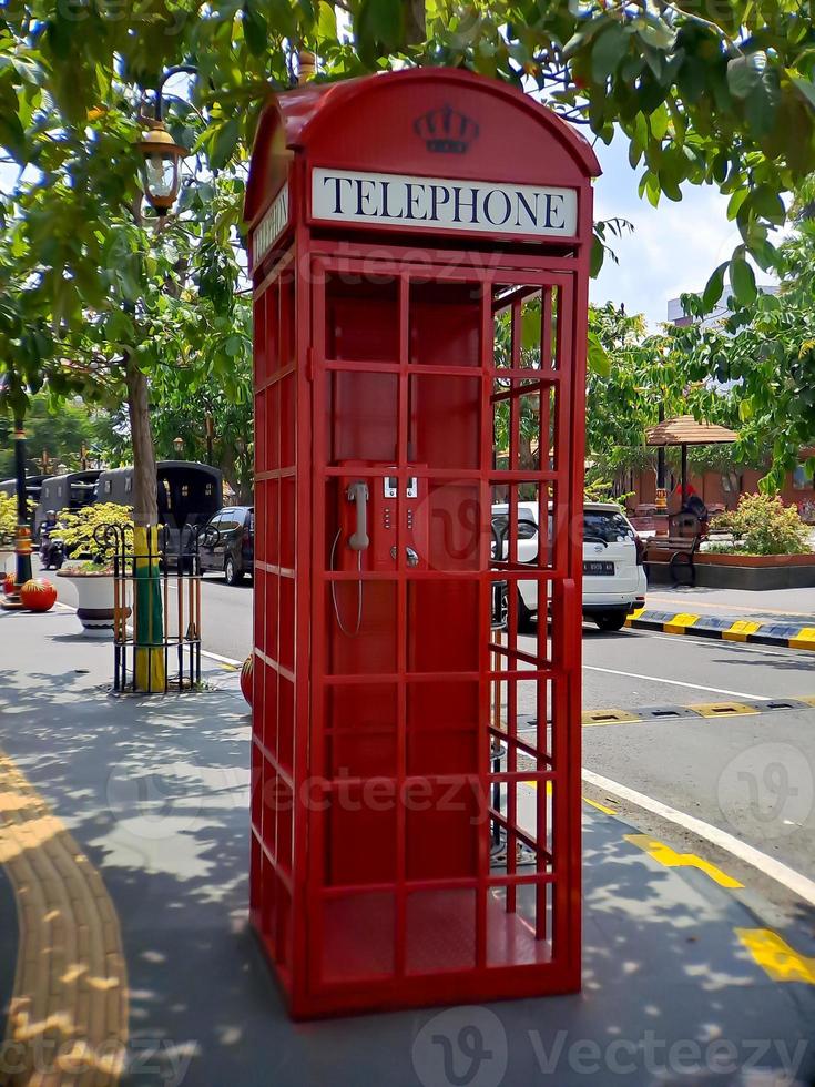 el viejo teléfono con cable rojo en el pasado, es como volver al pasado donde la gente solía usar teléfonos públicos. foto