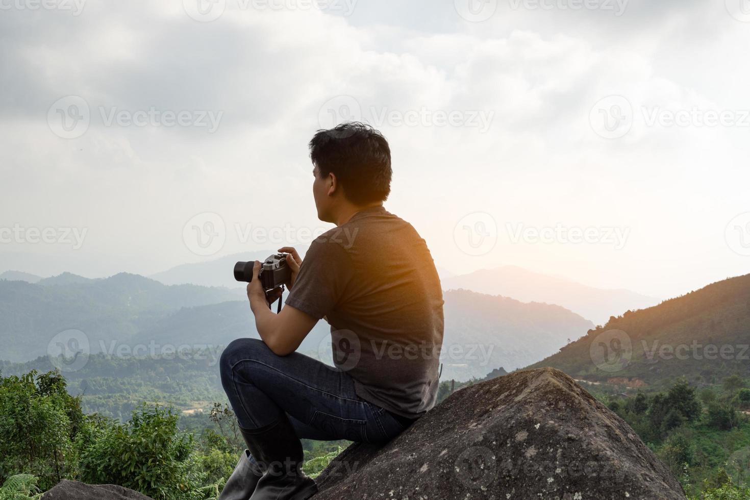 An Asian man catching camera travel alone at mountain and look at far a way, nature travel and environment concept computer sunrise light, copy space for individual text photo