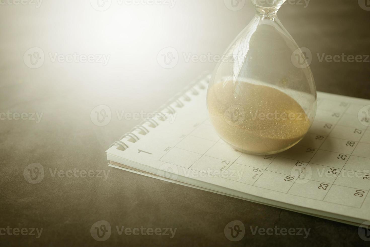 hourglass on a calendar, and flowing through the bulb of sandglass photo