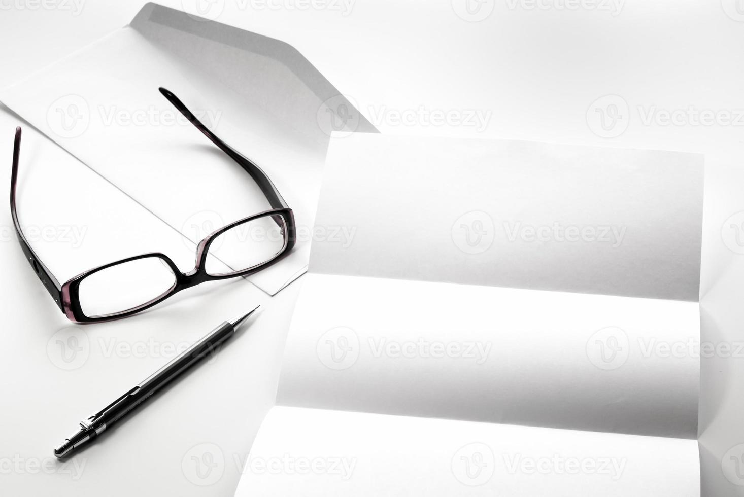 blank of letter paper and envelope with eyeglasses and pen photo