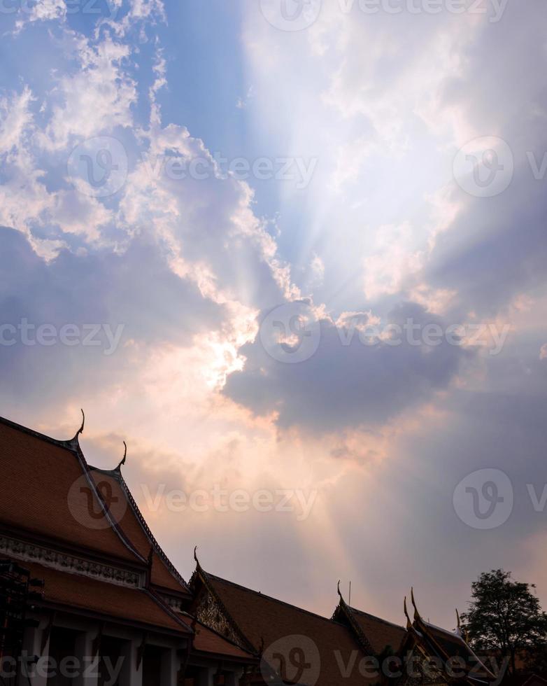 Sun beam behind the sunset clouds over the buddhist temple photo