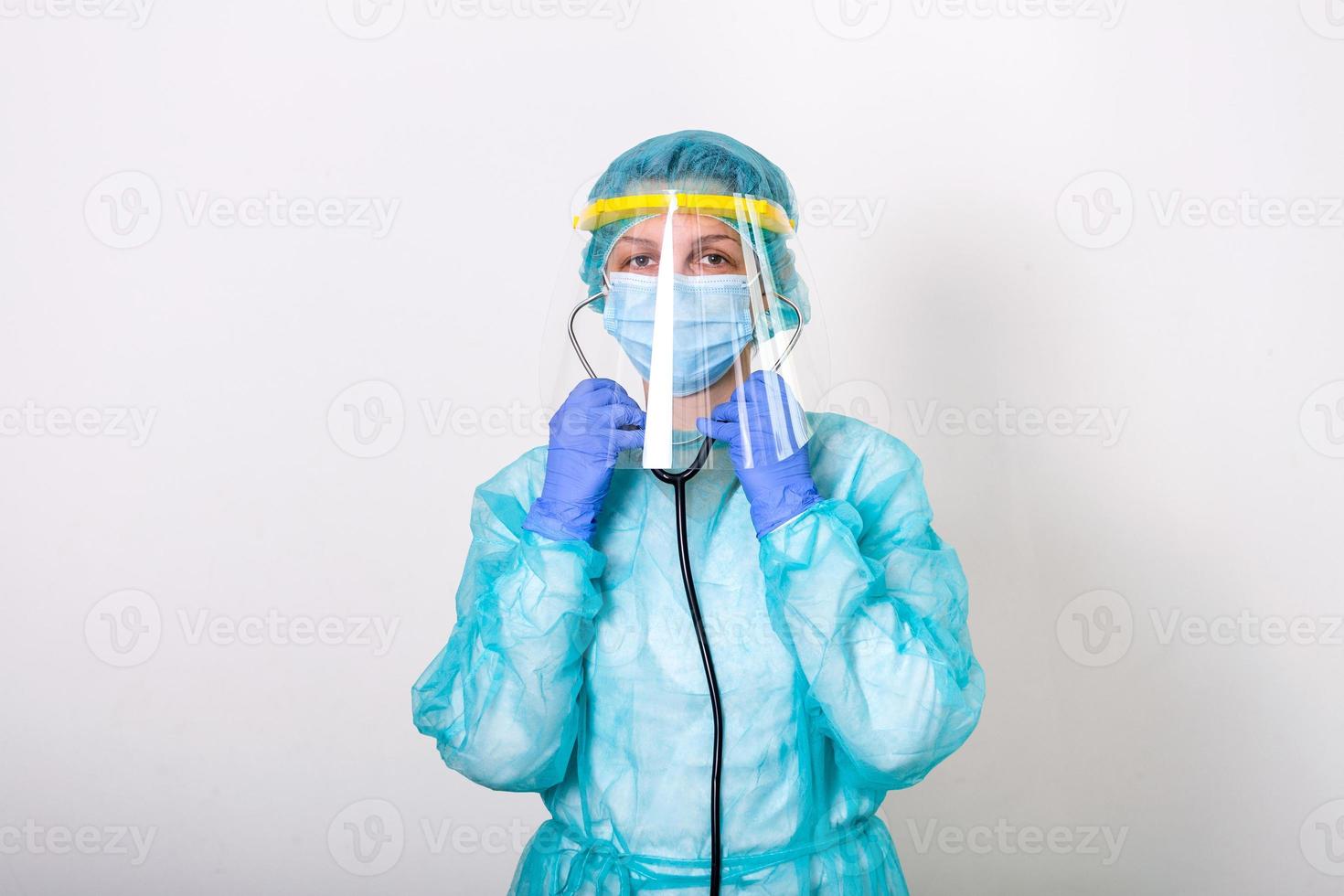 Doctor, nurse show how to wearing protection Suit for Fighting Covid-19 Corona virus with white background isolated. medical worker in full protective gear with face shield putting on her stethoscope photo