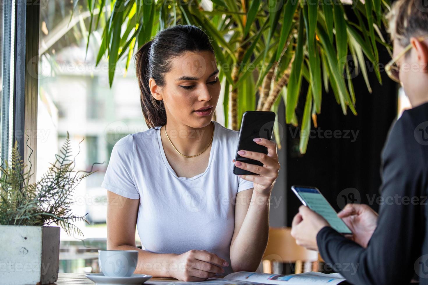 Mobile addiction concept, friends ignoring each other using smartphones relaxing in coffee shop, Obsessed with new apps or social networks, phone addicts lost in news online photo