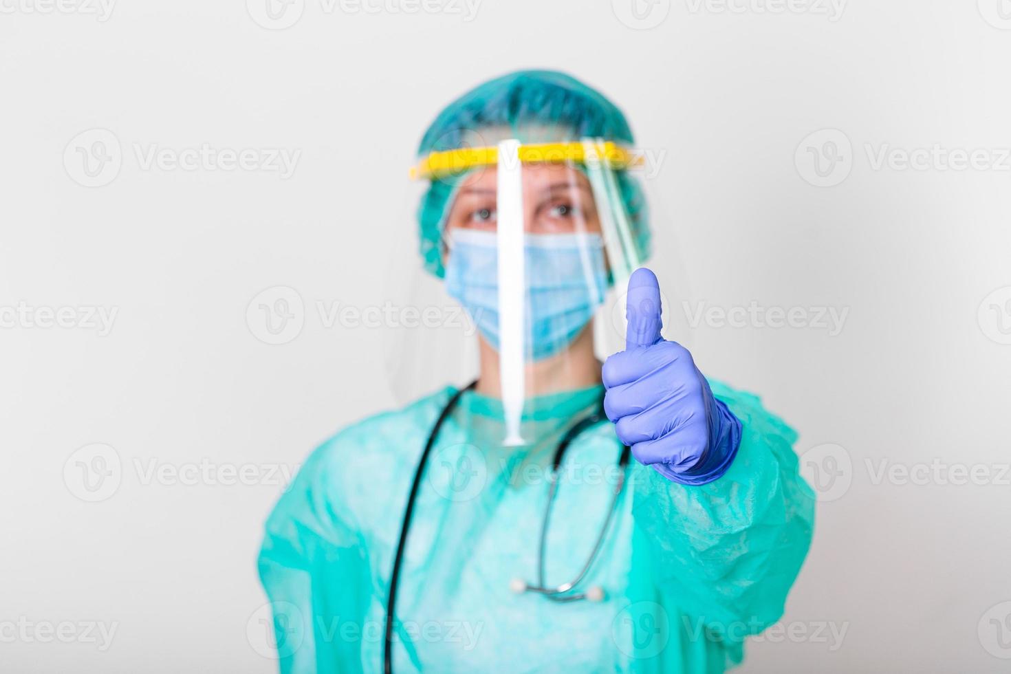 doctora que usa una suite de protección de ppe para luchar y detener la propagación del coronavirus covid-19 y el brote de covid-19 mostrando los pulgares hacia arriba foto