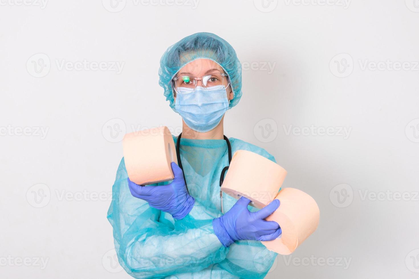 Doctor wearing PPE protection suite or nurse with a stethoscope holds a rolls of toilet paper. Lack of toilet paper in the quarantine of coronavirus, the concept of a shortage of things in stores photo