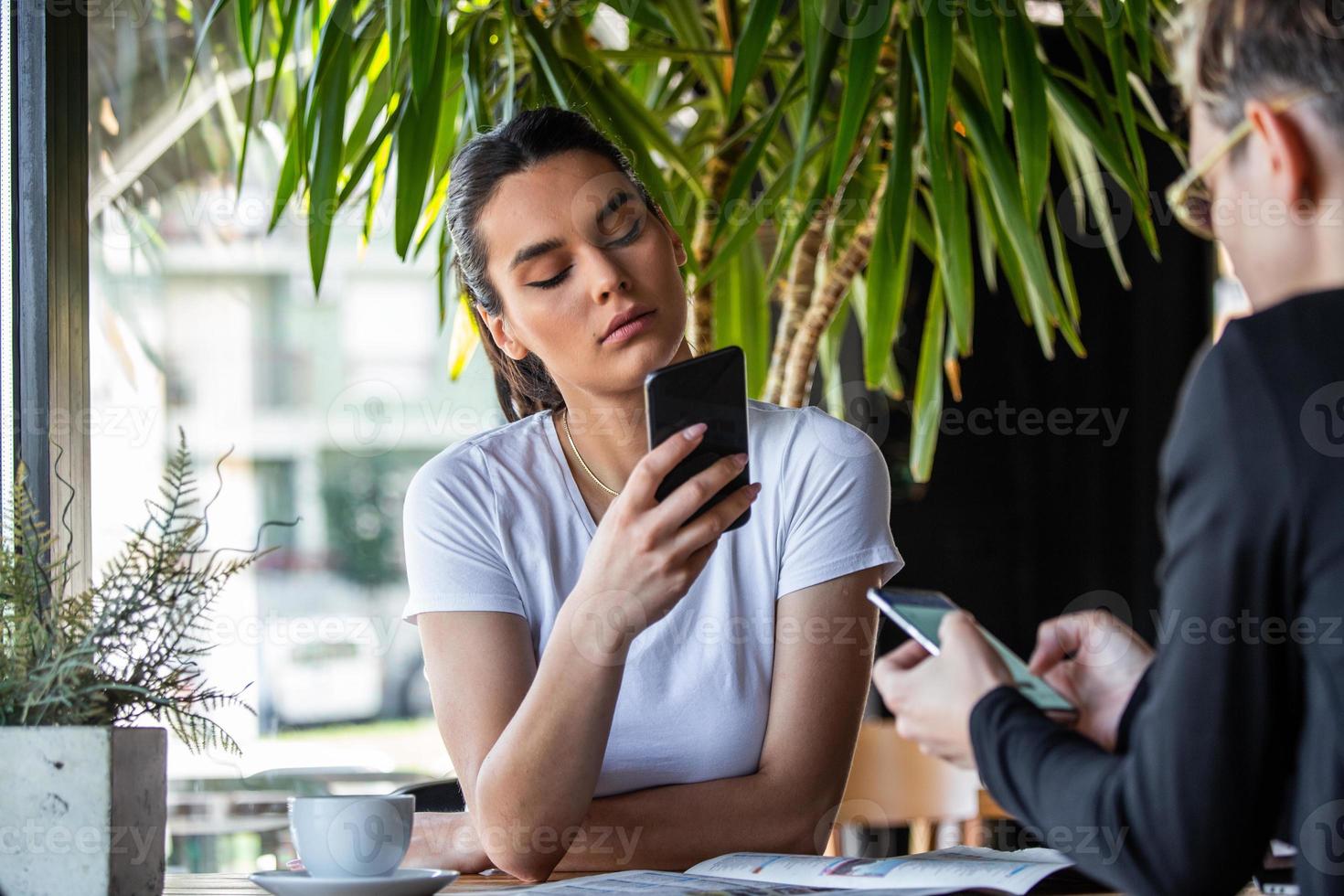 Mobile addiction concept, friends ignoring each other using smartphones relaxing in coffee shop, Obsessed with new apps or social networks, phone addicts lost in news online photo