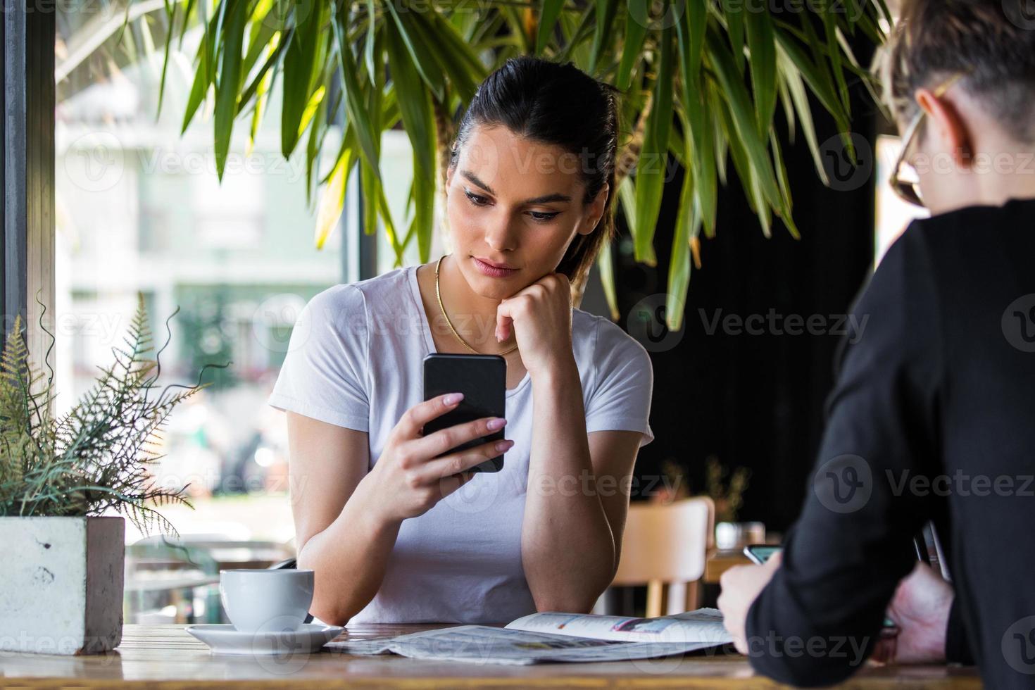 Mobile addiction concept, friends ignoring each other using smartphones relaxing in coffee shop, Obsessed with new apps or social networks, phone addicts lost in news online photo