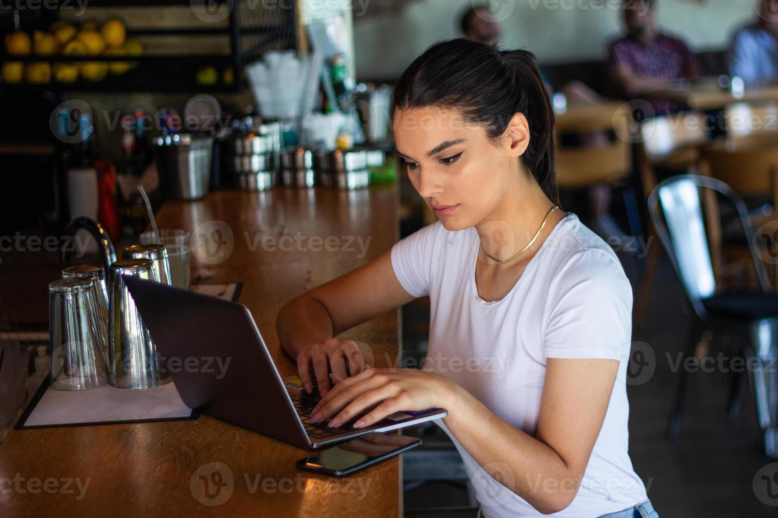 Young woman with coffee cup and laptop at coffe shop. Woman taking a break. Enjoying work from