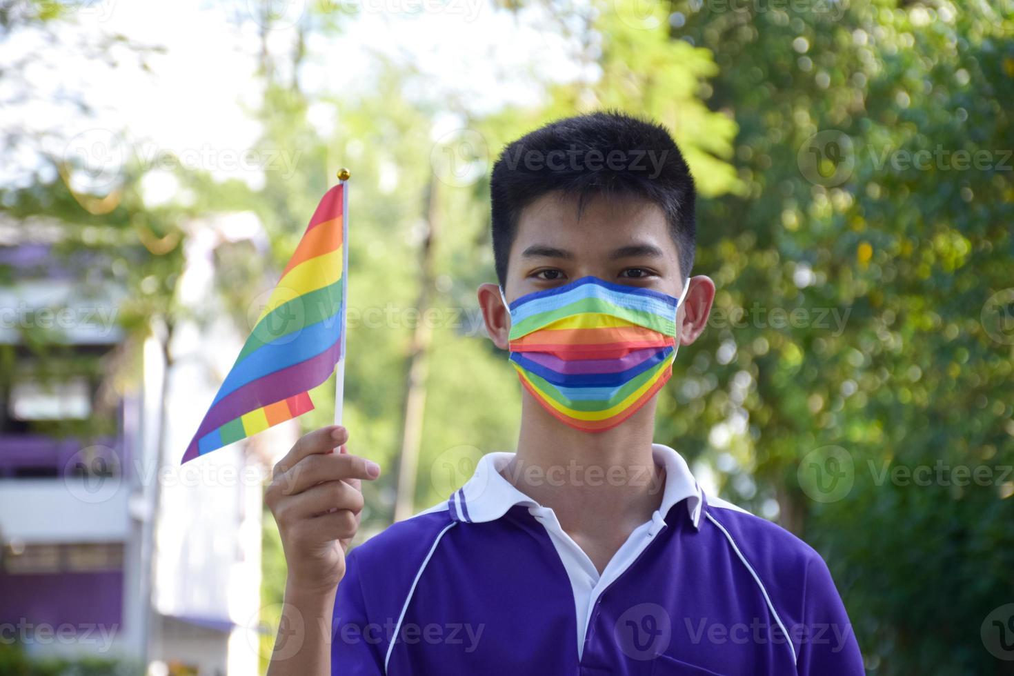 Portrait Asian young boy holds rainbow flag, LGBT symbol, in hands while joining his LGBT activity at school, concept for LGBT community celebration in pride month, June, 2023, around the world. photo