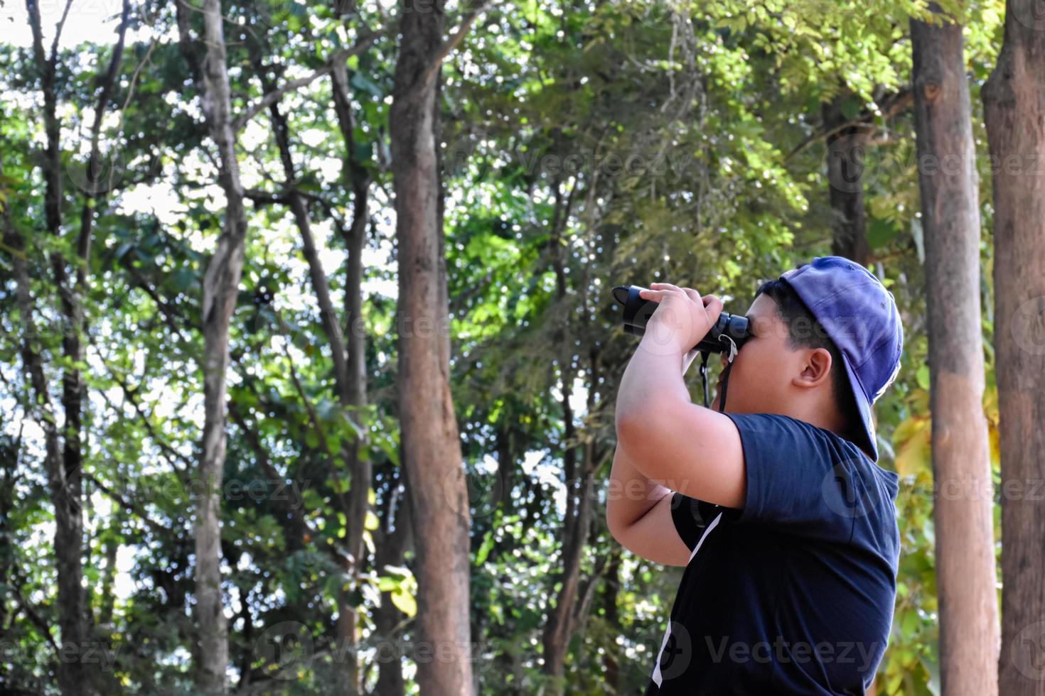 retrato de niños asiáticos usando binoculares para observar aves en el bosque tropical con sus amigos, idea para aprender criaturas y animales salvajes fuera del aula, enfoque suave. foto