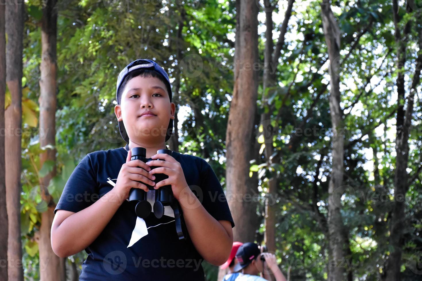 Portrait Asian boys using binoculars to watch birds in tropical forest with his friends, idea for learning creatures and wildlife animals outside the classroom, soft focus. photo