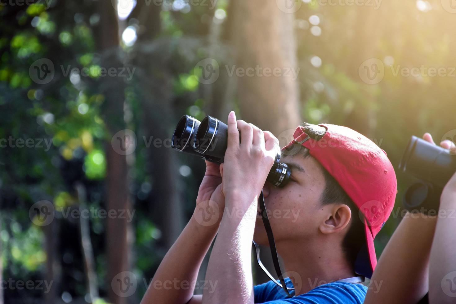 retrato de niños asiáticos usando binoculares para observar aves en el bosque tropical con sus amigos, idea para aprender criaturas y animales salvajes fuera del aula, enfoque suave. foto