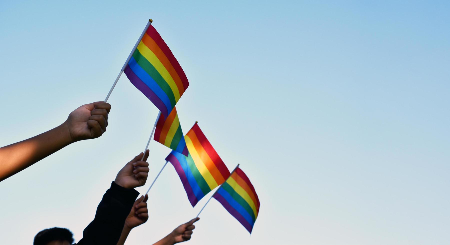 Rainbow flags, LGBT symbol, holding in hands, concept for LGBT community celebration in pride month, June, 2023, around the world. photo