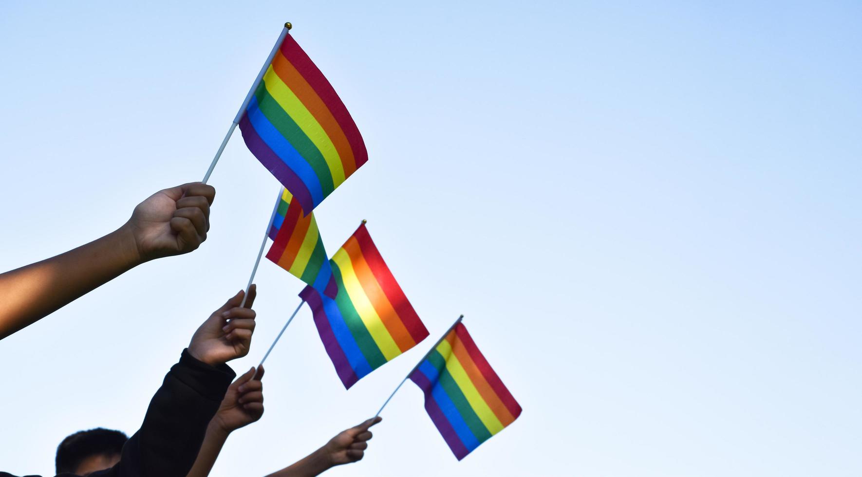Rainbow flags, LGBT symbol, holding in hands, concept for LGBT community celebration in pride month, June, 2023, around the world. photo