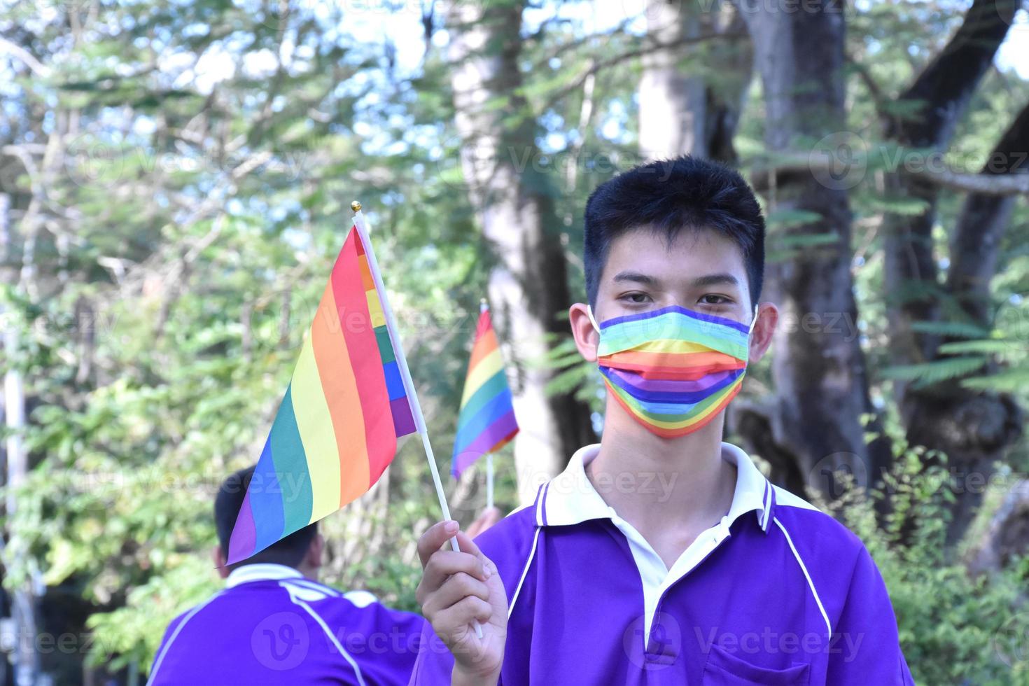 Portrait Asian young boy holds rainbow flag, LGBT symbol, in hands while joining his LGBT activity at school, concept for LGBT community celebration in pride month, June, 2023, around the world. photo