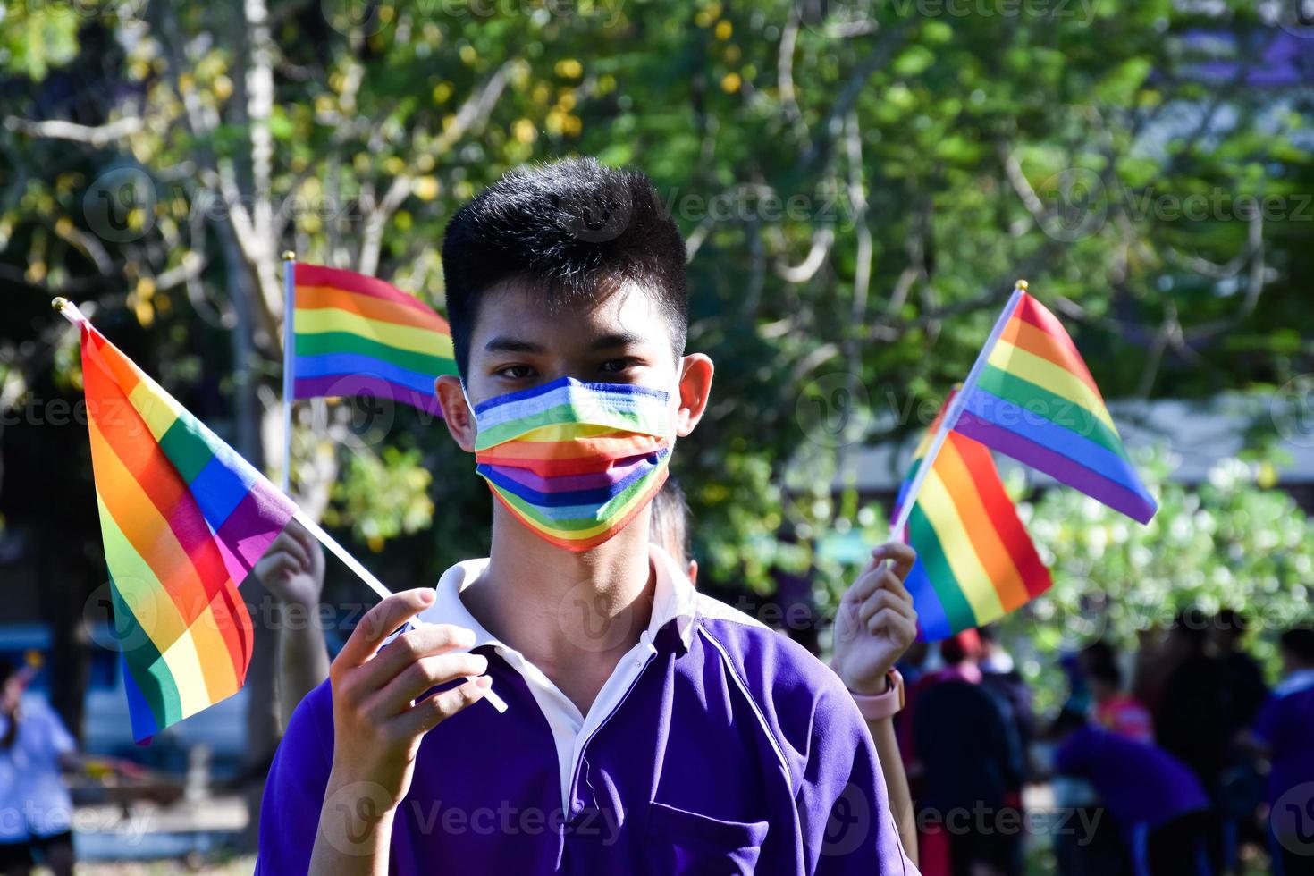 Portrait Asian young boy holds rainbow flag, LGBT symbol, in hands while joining his LGBT activity at school, concept for LGBT community celebration in pride month, June, 2023, around the world. photo