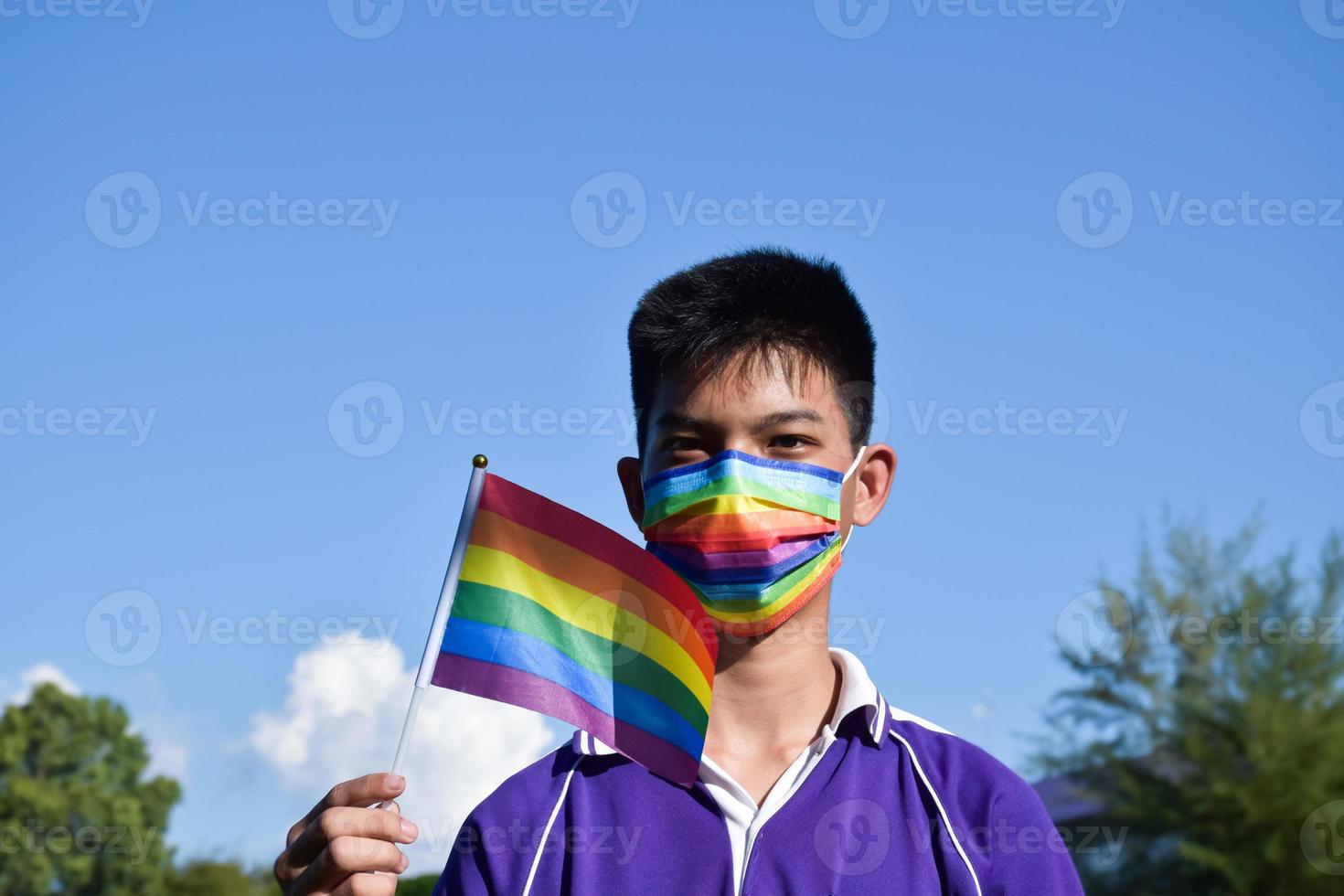 Portrait Asian young boy holds rainbow flag, LGBT symbol, in hands while joining his LGBT activity at school, concept for LGBT community celebration in pride month, June, 2023, around the world. photo