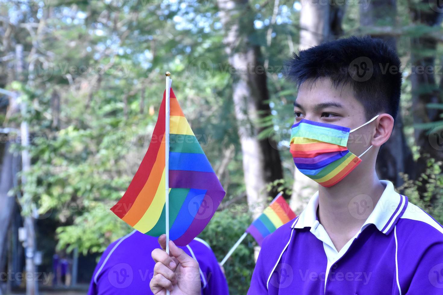 Portrait Asian young boy holds rainbow flag, LGBT symbol, in hands while joining his LGBT activity at school, concept for LGBT community celebration in pride month, June, 2023, around the world. photo