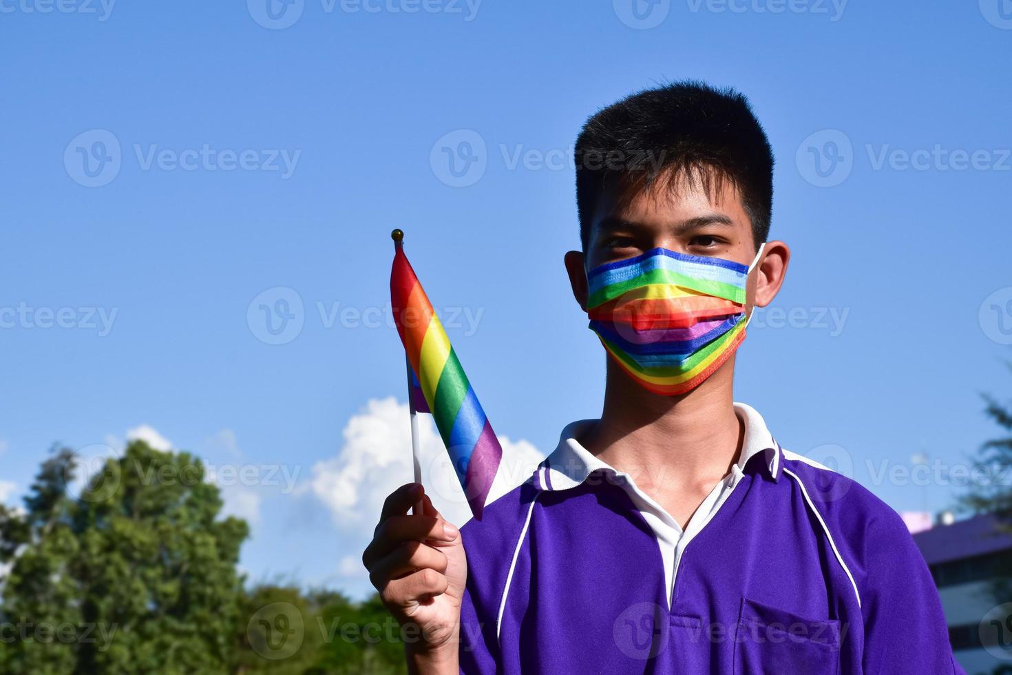 Portrait Asian young boy holds rainbow flag, LGBT symbol, in hands while joining his LGBT activity at school, concept for LGBT community celebration in pride month, June, 2023, around the world. photo