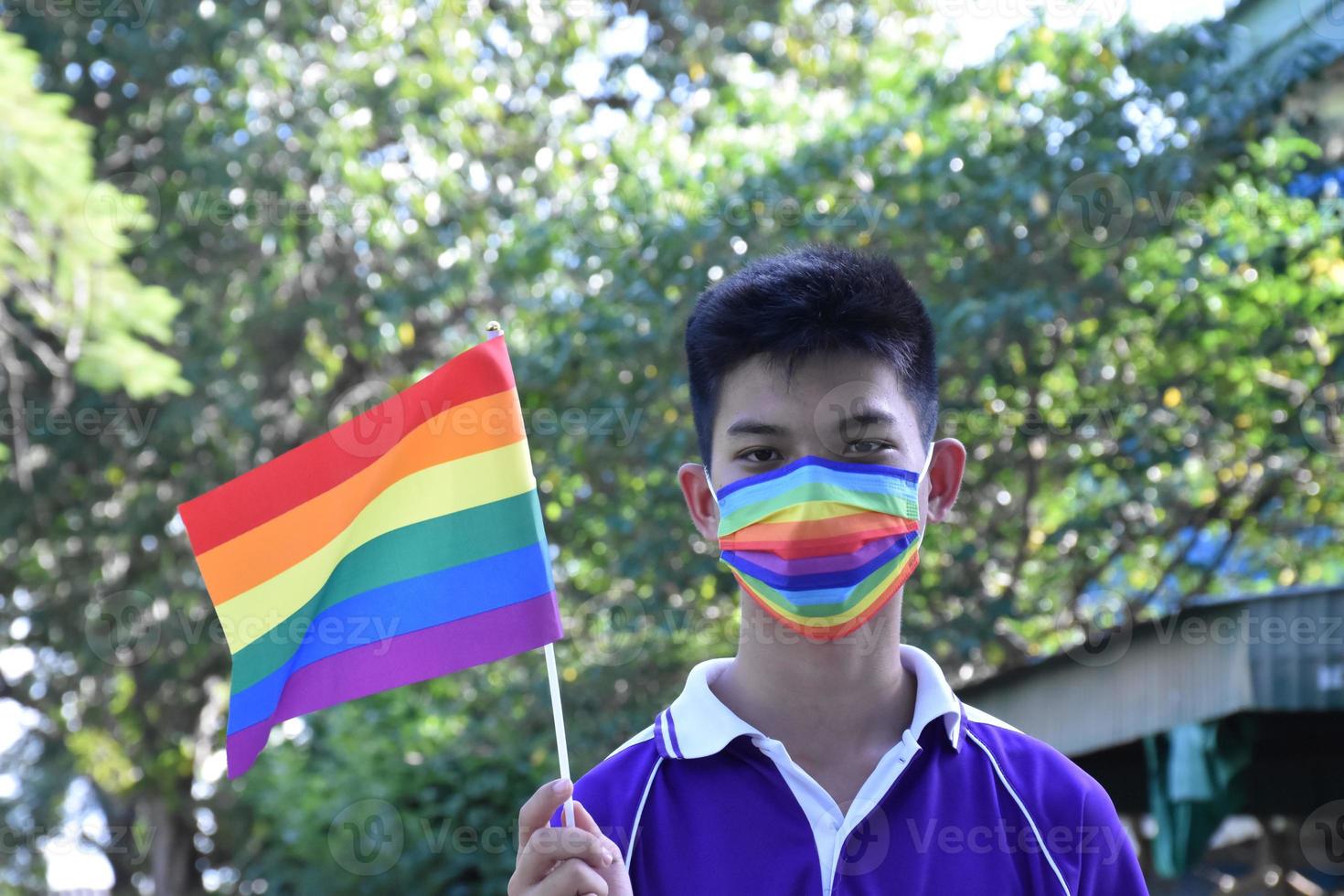 Portrait Asian young boy holds rainbow flag, LGBT symbol, in hands while joining his LGBT activity at school, concept for LGBT community celebration in pride month, June, 2023, around the world. photo