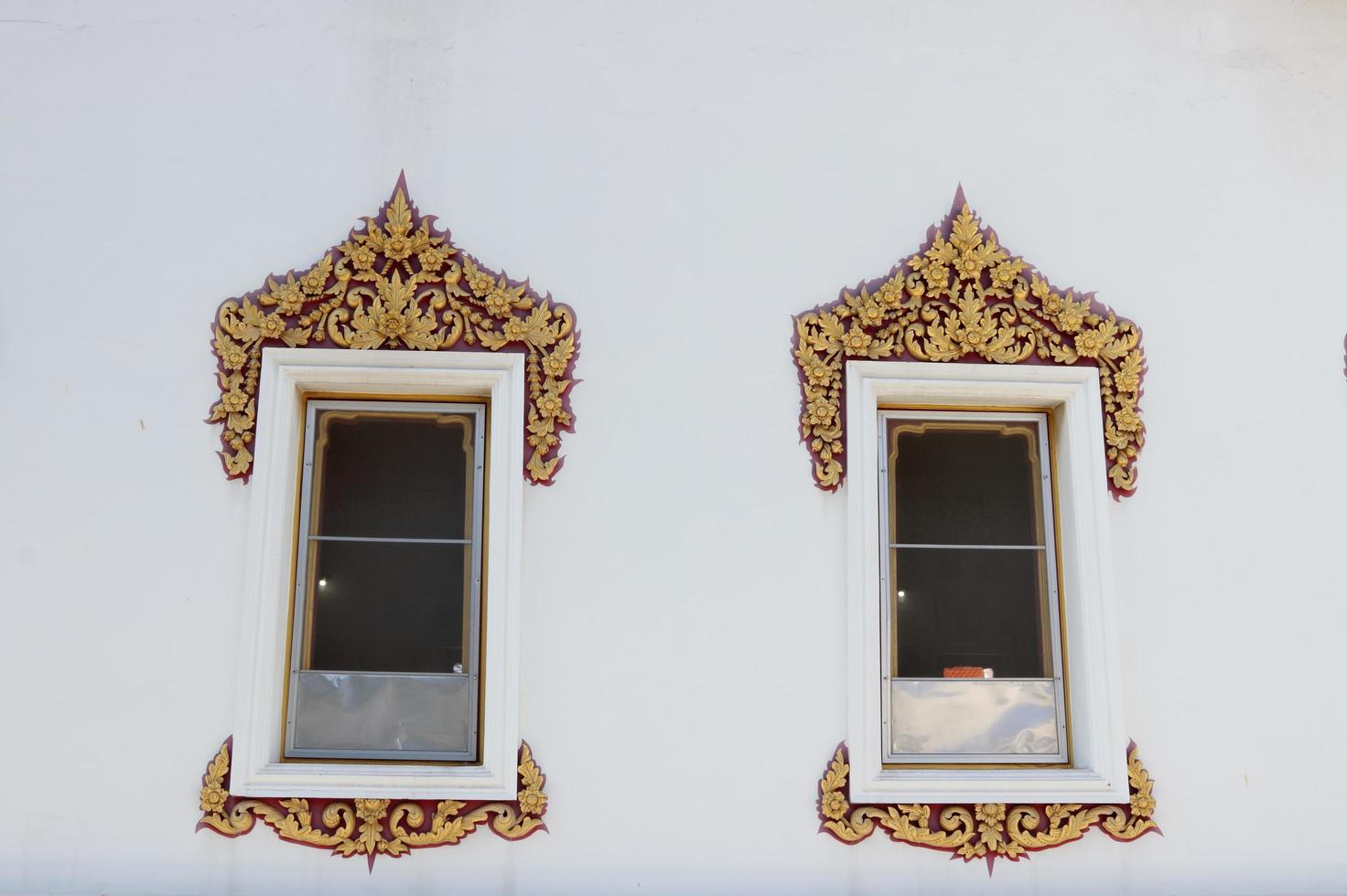 marco de color dorado y rojo de ventanas de madera pintadas de blanco en una pared de cemento pintada de blanco en un antiguo estilo tailandés nativo de construcción en un templo en bangkok, tailandia. foto