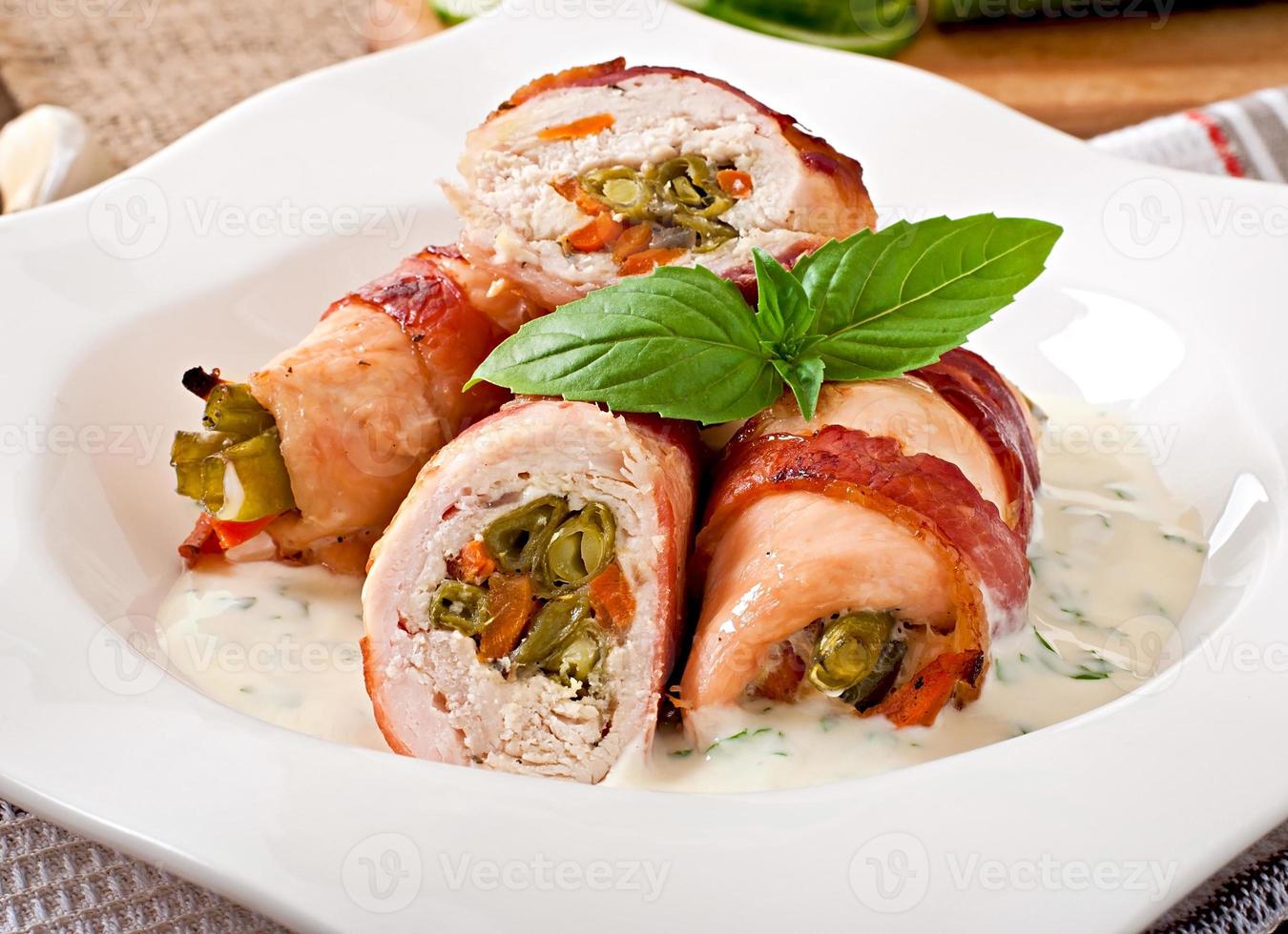 Delicious chicken rolls stuffed with green beans and carrots wrapped in strips of bacon photo