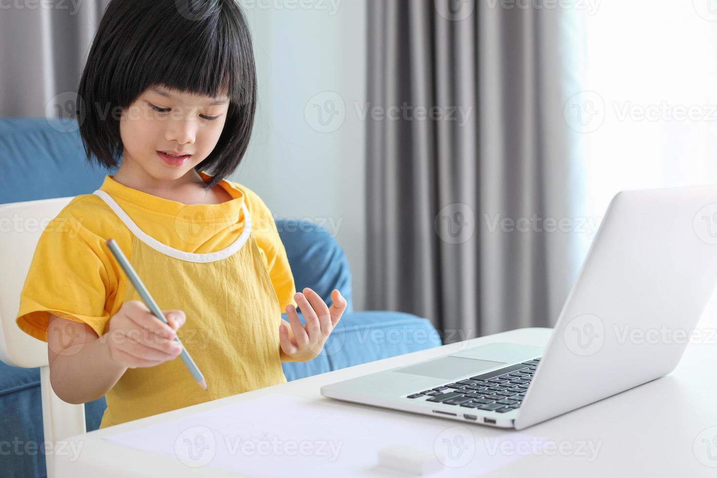 little asian girl student study online using laptop computer at home photo