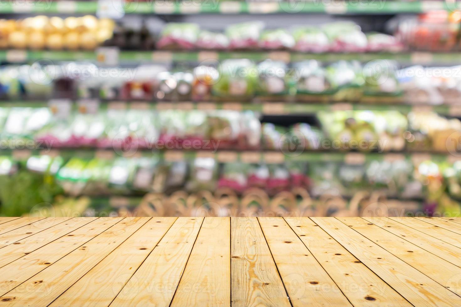 Wood table top with vegetables on grocery store shelves blurred background photo
