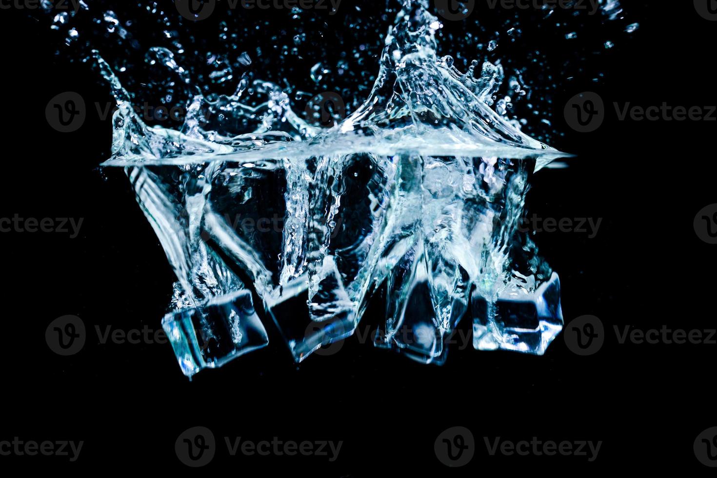 cubos de hielo en agua con burbujas sobre fondo negro foto