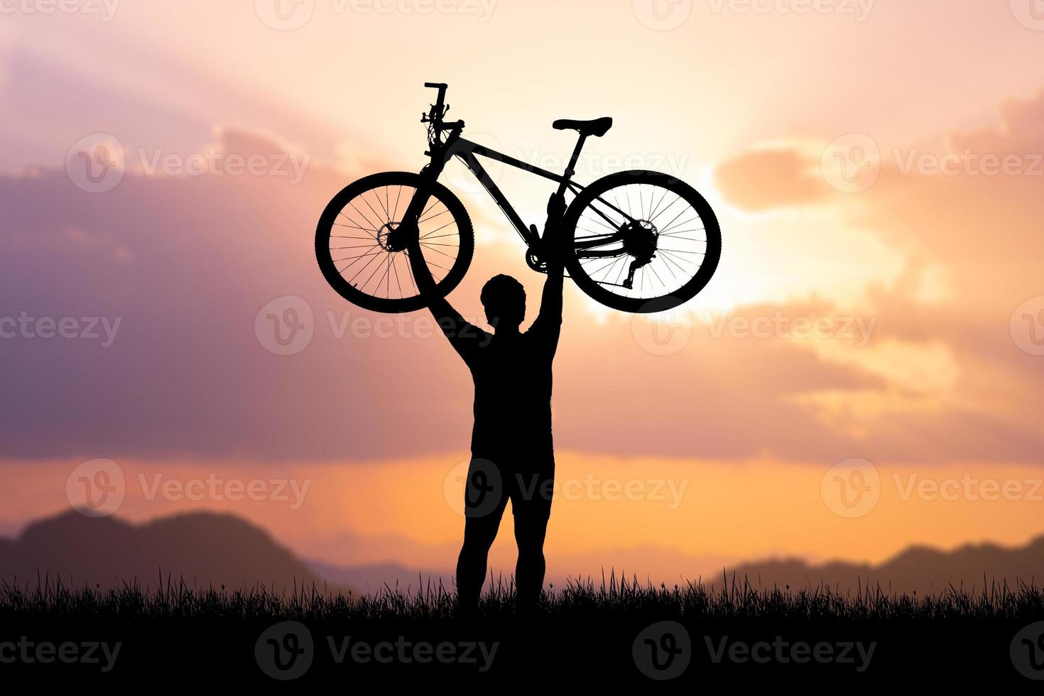 Man holds a bicycle on top of a mountain. concept of success and victory photo