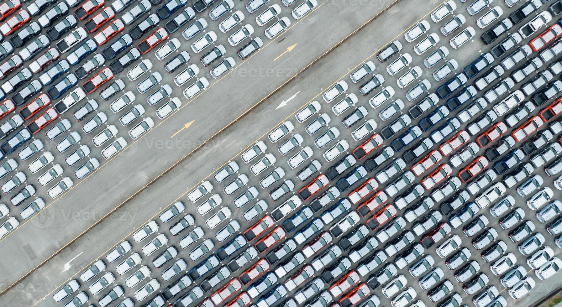 vista aérea de las existencias de autos nuevos en el estacionamiento de la fábrica. arriba ver muchos autos estacionados en fila. industria automotriz. negocios de logística y cadena de suministro. importar o exportar autos nuevos en el almacén cerca del puerto. foto