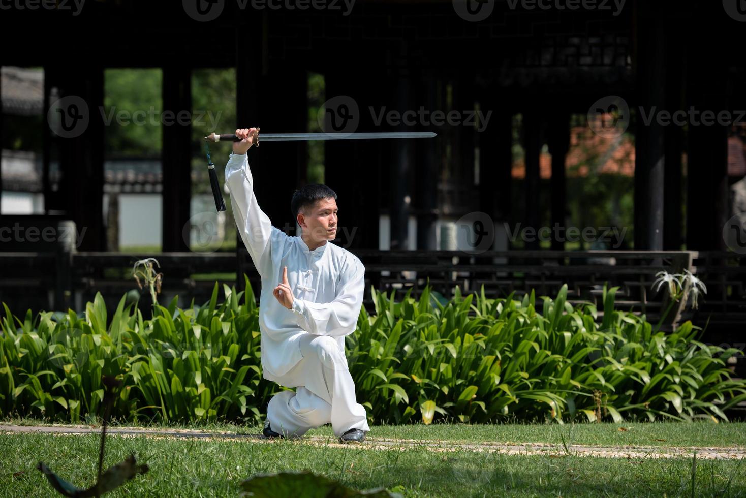 Young man practicing traditional Tai Chi Sword, Tai Ji in the park for healthy, traditional chinese martial arts concept on natural background . photo