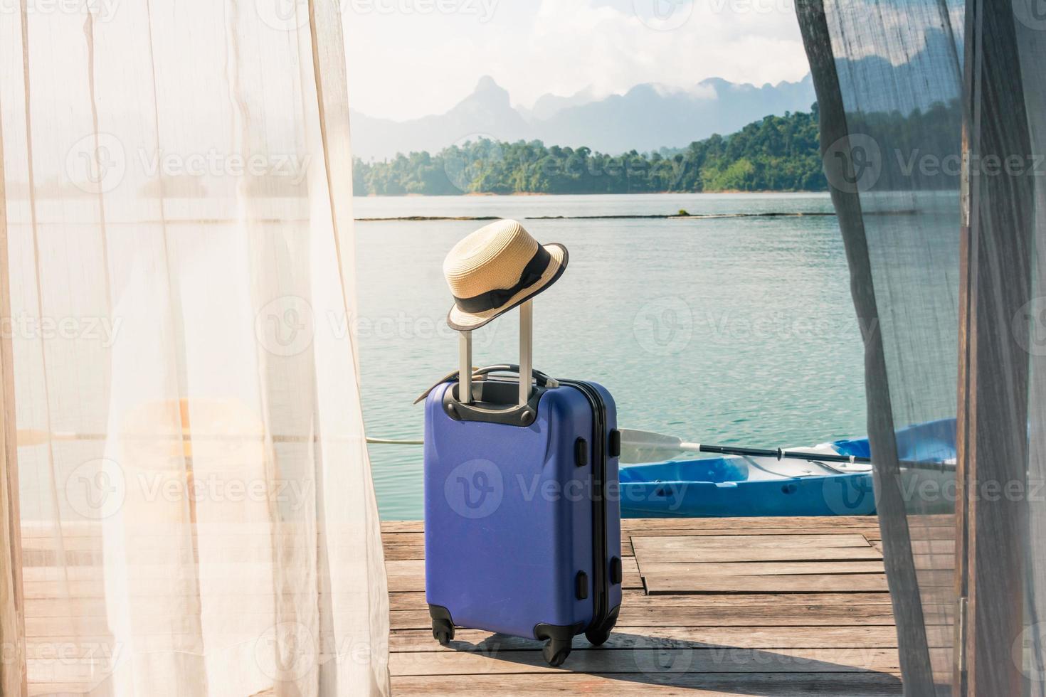 tiempo para viajar y relajarse, maleta de viaje con sombrero de pie en el suelo fuera del dormitorio en el lago y la playa. foto