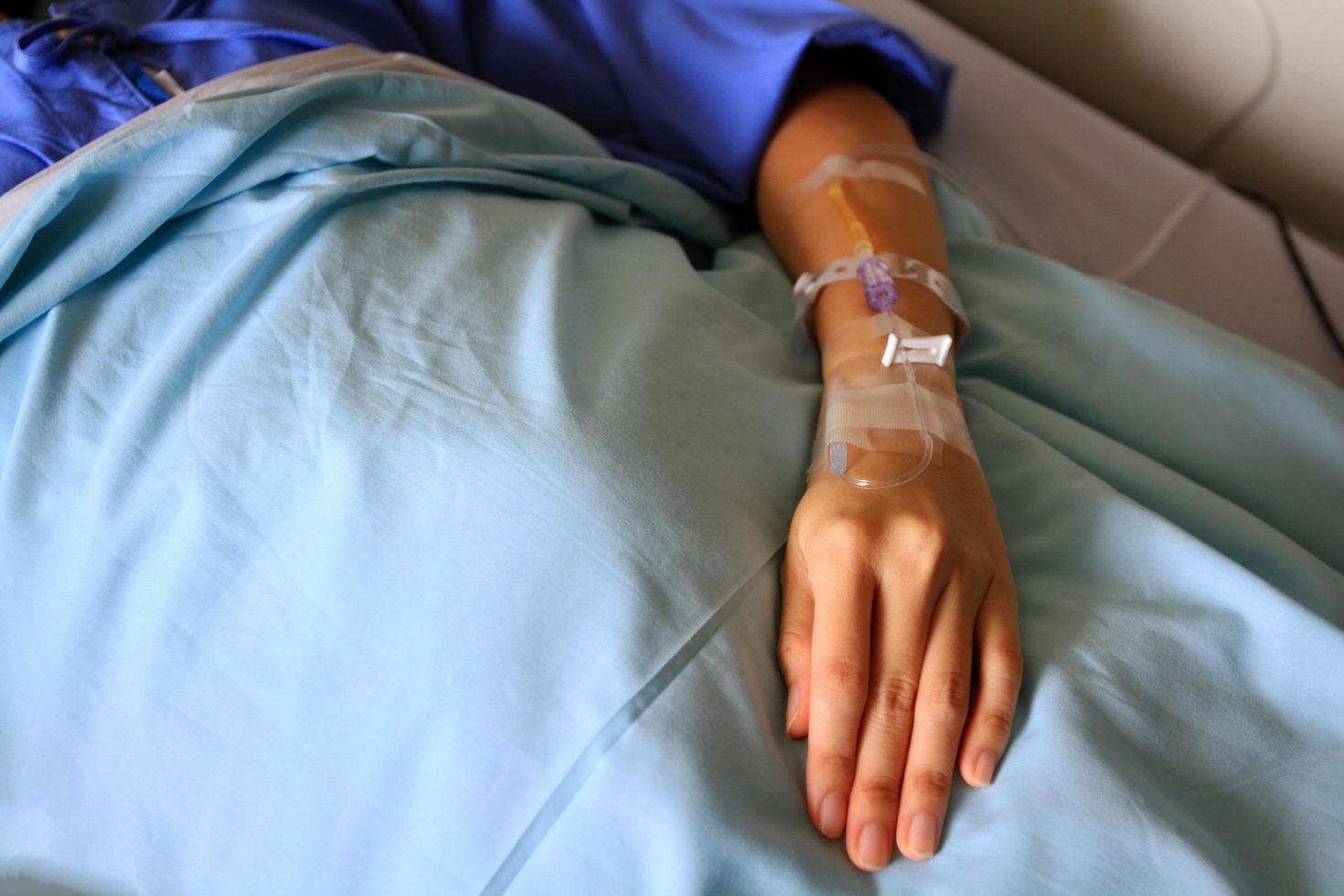 las manos o el brazo del paciente que dan la solución salina en la cama con espacio para copiar. saludable, medicina o médica e inyección. la gente cura la enfermedad y la fiebre en el concepto de hospital o clínica. foto