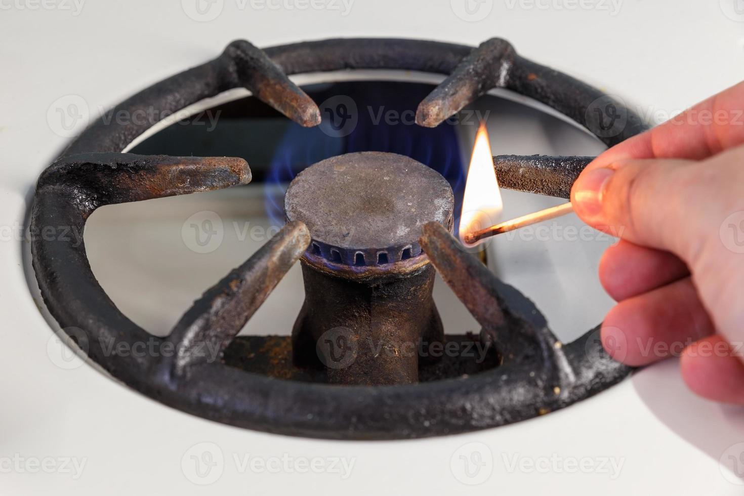 A man lighting a gas stove with a match. Vintage gas burner. photo