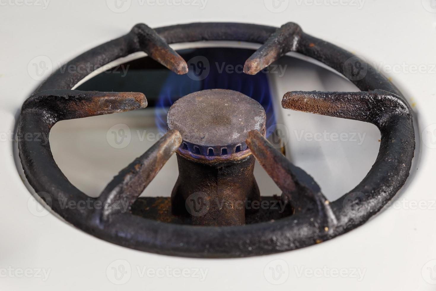 The gas burner on the stove is on and burns with a blue flame. Vintage gas burner. photo