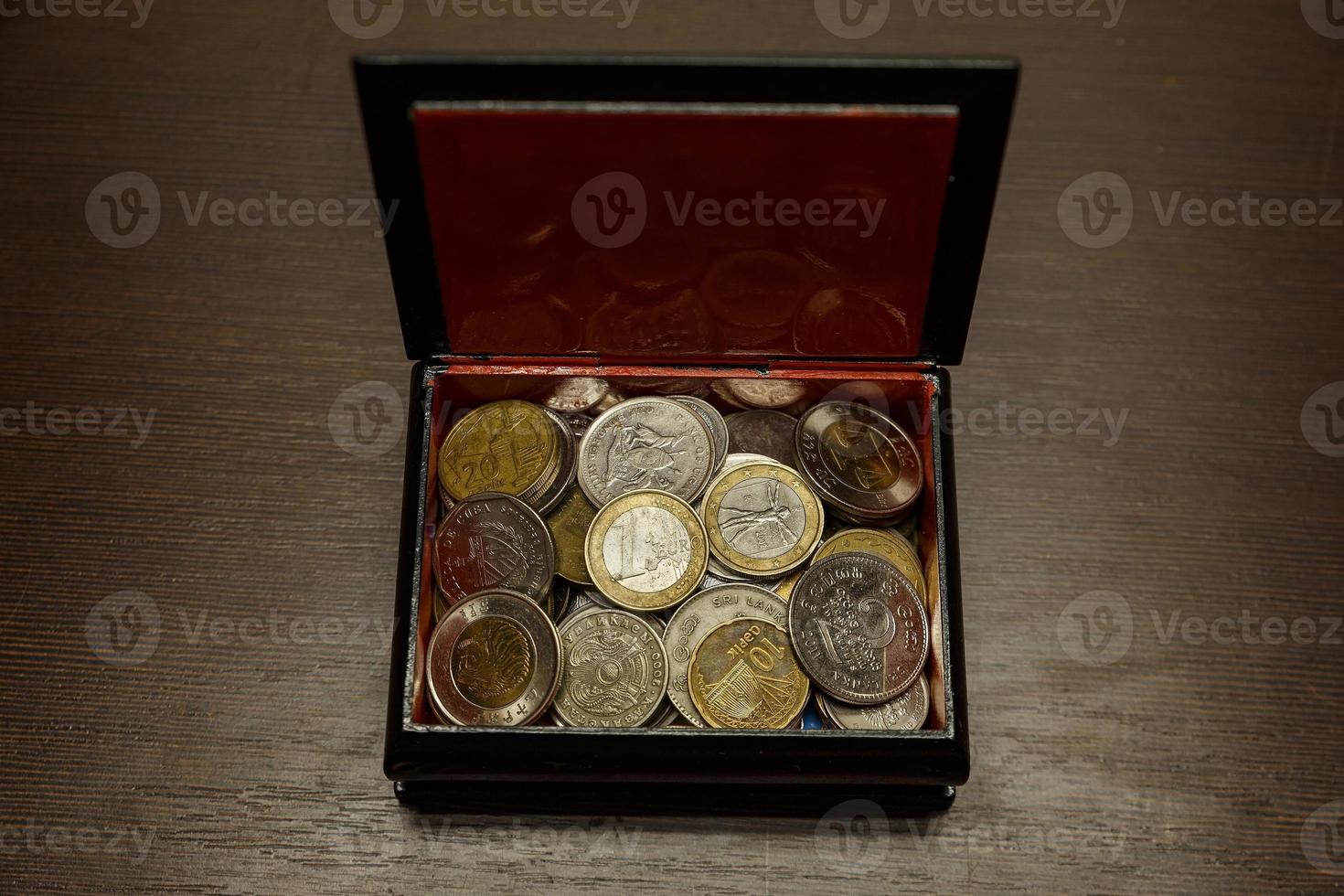 Open casket with coins from different countries. Keeping coins in a box. Closeup top view photo