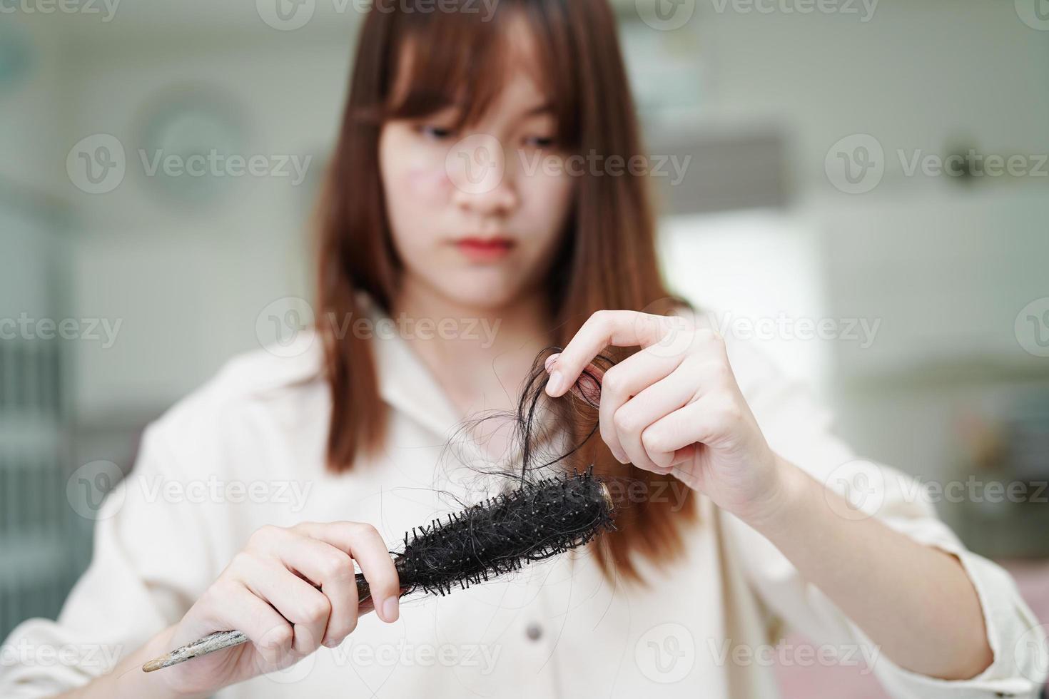 Asian woman have problem with long hair loss attach to comb brush. photo