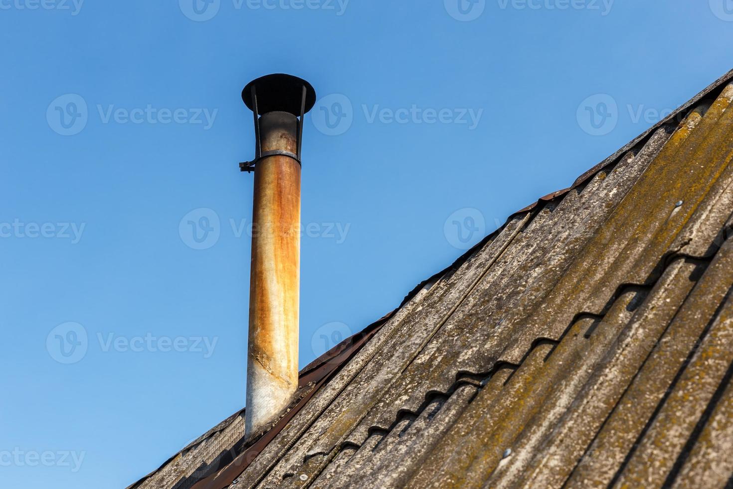 Chimney pipe on the roof of the house against the blue sky. photo