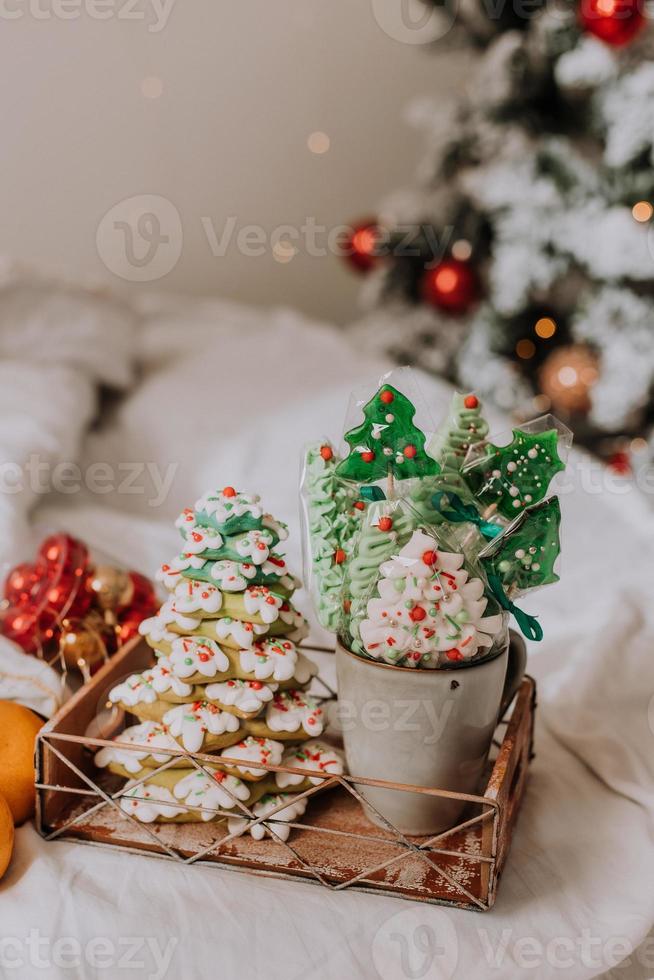 dulces navideños, pan de jengibre pintado con glaseado, piruletas y merengues en forma de árboles de navidad y mandarinas en una bonita bandeja. tortas caseras deliciosa comida para las vacaciones de invierno foto