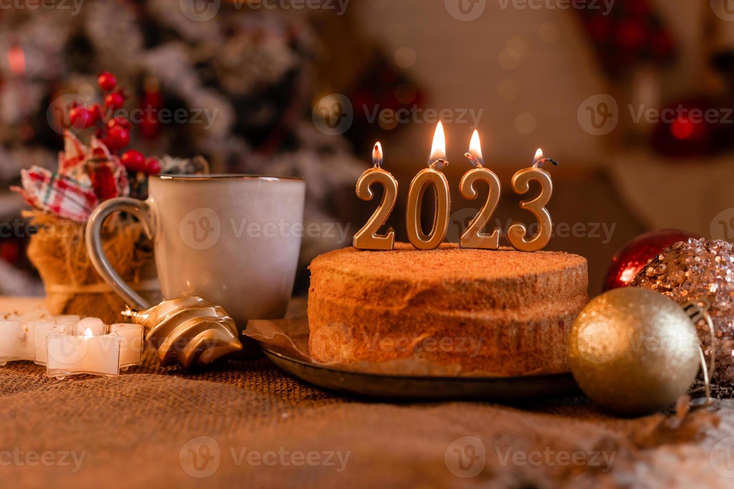 pastel de miel casero en la cocina con velas 2023. acogedor año nuevo en casa. Feliz Navidad. foto de alta calidad