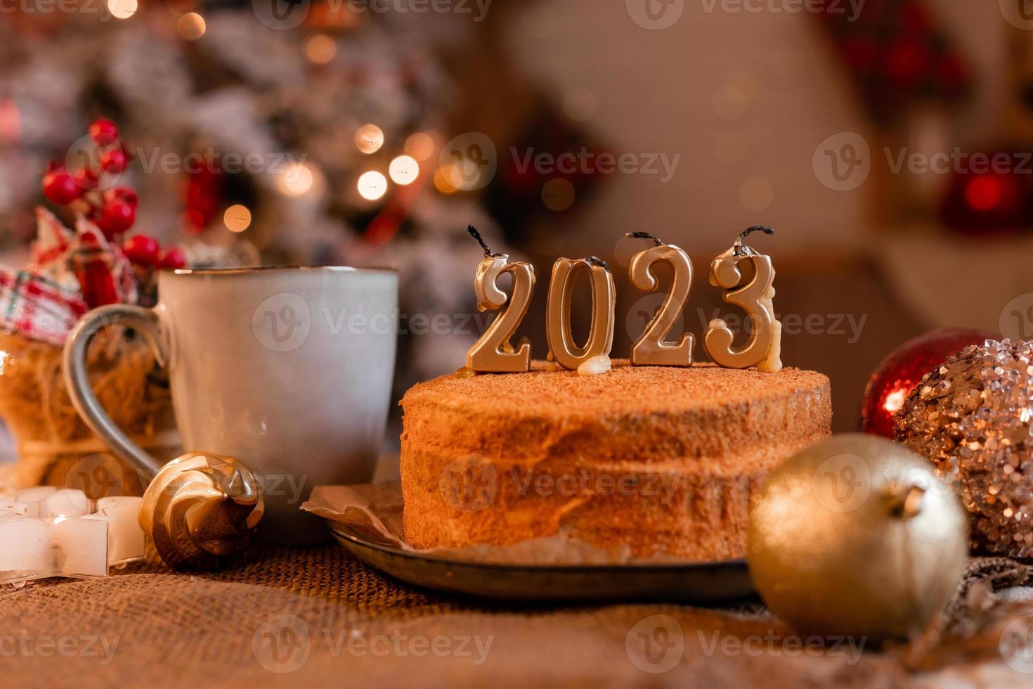 pastel de miel casero en la cocina con velas 2023. acogedor año nuevo en casa. Feliz Navidad. foto de alta calidad