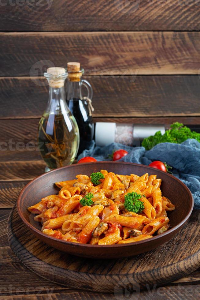 pasta penne en salsa marinara con mejillones, cebolla y perejil. Penne de pasta italiana clásica foto