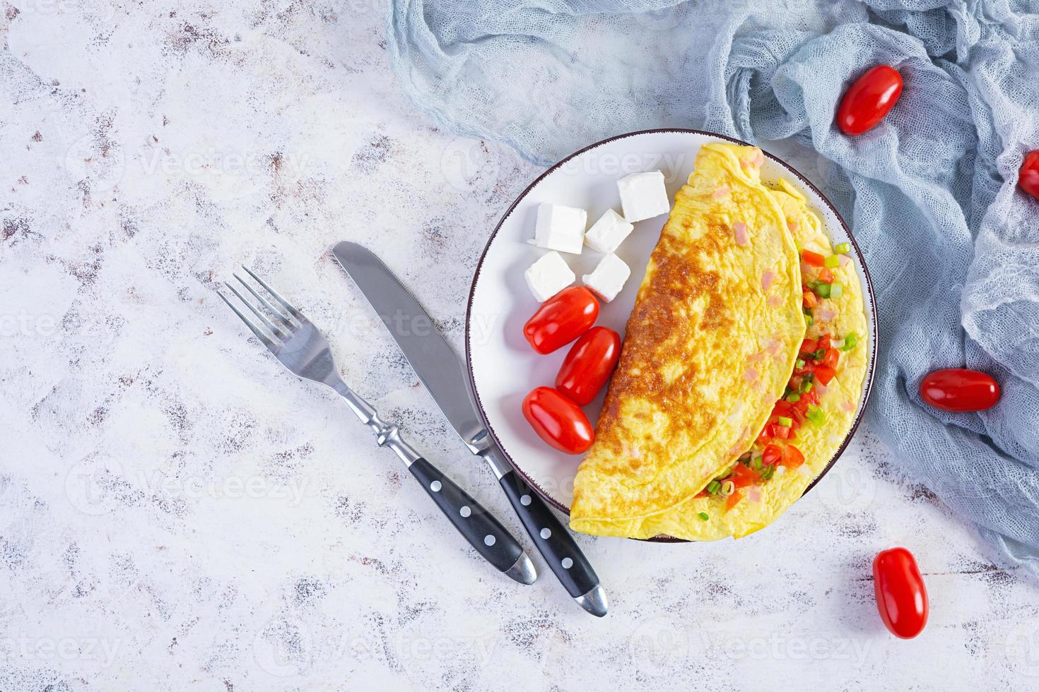 Fried omelette with beef, tomato, onion and herbs. Delicious breakfast with scrambled eggs. Top view photo